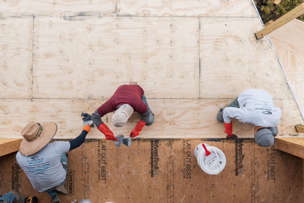 An aerial view of three men working on a home.